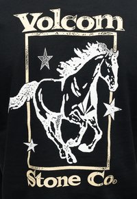 Άλογο λευκό που τρέχει μέσα σε ορθογώνιο πλαίσιο μπεζ με τρία αστέρια, με τη λέξη "Volcom" από πάνω και "Stone Co." από κάτω σε μαύρο φόντο.