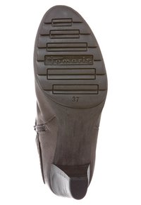 Suela de bota negra con goma texturizada para agarre, que presenta estrías horizontales y una marca. Talla '37' estampada cerca del talón.