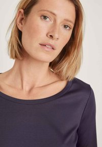 Marineblauwe top met ronde hals van zachte stof, met driekwart mouwen en een gladde textuur, met een getailleerde pasvorm.