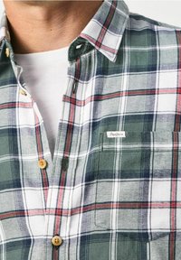 Knappupp skjorta i grön, vit och röd rutöverfång. Har en bröstficka, rundad krage och träknappar. Applikationsetikett finns.