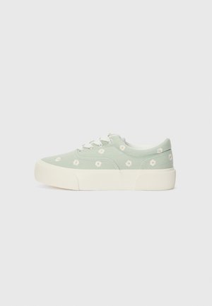 Light green low-top sneaker with white laces and sole, decorated with small white daisy flower patterns.