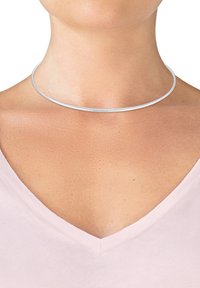 Metallic sølv choker halskæde, cirkulært design, glat overflade, tynd profil, båret omkring halsen, fremhæver kravebenområdet.