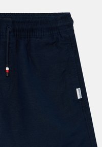 Mörkblå herrshorts med elastisk midja och snörning, sidofickor och en liten logglabel vid nederkanten.