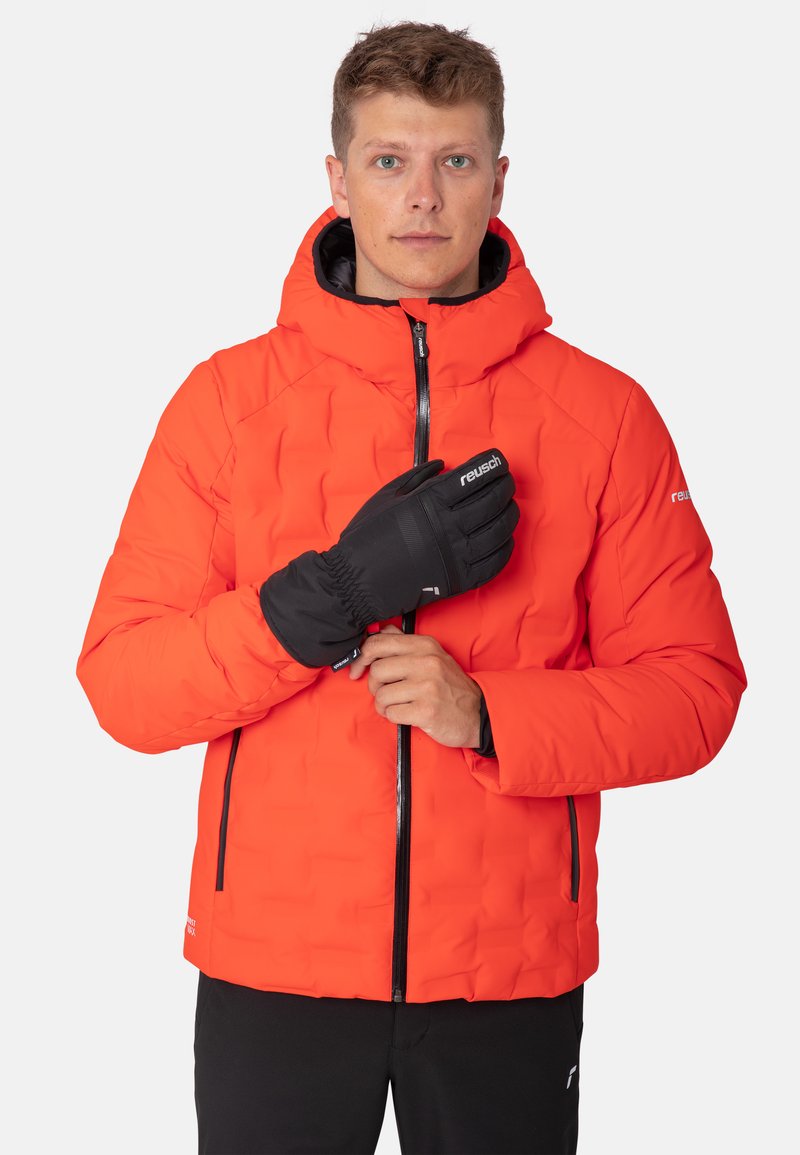 Leuchtend orangefarbene Daunenjacke mit Reißverschluss und Kapuze. Mit schwarzem Reißverschluss und Akzenten. Das Modell trägt schwarze Handschuhe. Glatte Textur.