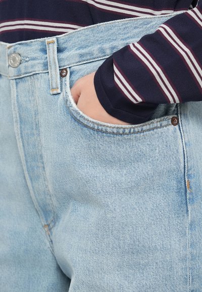 Jasnoniebieskie dżinsy z prostą nogawką, zapinane na guzik, z szlufkami na pasek i przednią kieszenią, wykonane z miękko teksturowanej tkaniny.