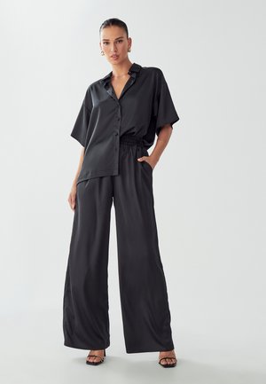 Black satin two-piece outfit featuring a short-sleeve button-up shirt and wide-leg pants with an elastic waistband.