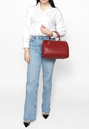 Borsa a mano in pelle rossa con accessori dorati, forma strutturata e due manici. Superficie texturizzata con due etichette attaccate.