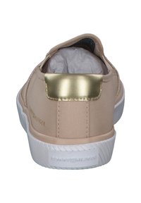 Beżowe płócienne trampki z złotym akcentem na pięcie, białą gumową podeszwą i teksturowanym materiałem. Zawierają logo w pobliżu pięty.