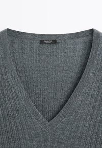 Pull gris à col en V en maille torsadée avec col côtelé et étiquette "Massimo Dutti" à l'arrière du col, fabriqué en Chine.
