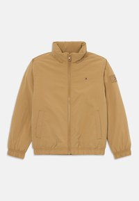 Lysbrun zip-up jakke med ståkrave, elastiske manchetter og kant, frontlommer og lille Tommy Hilfiger-logo på brystet og ærmet.