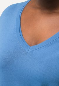 Ljusblå, stretchnylon topp med v-ringning och en slät textur, med en djup halsringning och subtil sömnad längs kanterna.