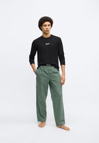 Cămașă neagră cu mâneci lungi și logo-ul "BOSS", asortată cu pantaloni verde în carouri, cu croială lejeră și talie elastică.