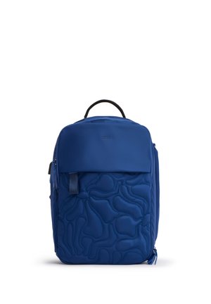 Zaino blu con motivo astratto trapuntato, maniglia superiore, tasca frontale con cerniera e cerniera del comparto principale su sfondo bianco semplice.