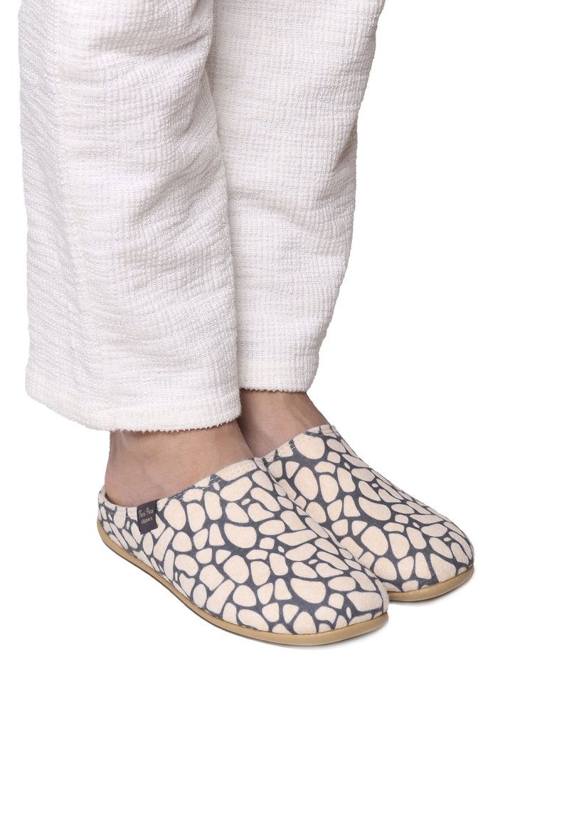 Slip-on skor med ett strukturerat ljusbeige och mörkt mönster, med en mjuk tygövre och en flexibel gummisula.