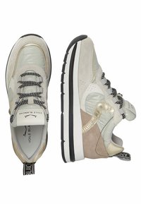 Zapatillas de color claro con una mezcla de materiales texturizados, incluyendo ante y acentos brillantes, con cordones y suela a rayas en negro y blanco.