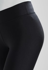 Leggings neri realizzati in un tessuto liscio ed elasticizzato con una vita alta. Caratterizzati da un design elegante e aderente senza cuciture visibili.