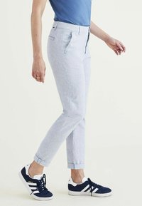 Lichtblauwe gestreepte broek met een slim fit, met opgerolde enkels en zijzakken, gecombineerd met donkerblauwe sneakers met witte accenten.