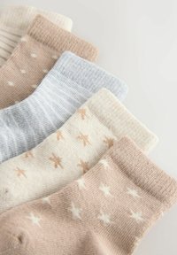 Vijf paar zachte gebreide sokken in beige, crème en lichtblauwe tinten met ster- en stippenpatronen, gerangschikt in een uitwaaierende rij.