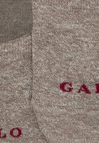 Calze a crew lavorate a maglia in un motivo mélange marrone e beige, con scritte bordeaux su un lato. Texture morbida con una sensazione di imbottitura.