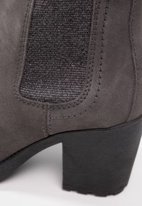 Bottine en daim gris foncé avec panneau latéral élastique texturé et talon noir épais.