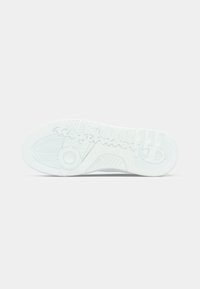 Weiße Sneakersohle aus strukturiertem Gummi mit Mustern und einem runden Designelement. Glatte Oberfläche und deutliche Profil-Details.