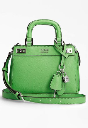 Felgroene Guess-handtas met bovenhandvatten, afneembare schouderriem, zilveren slot- en sleutelbedeltjes en Guess-logo aan de voorkant.