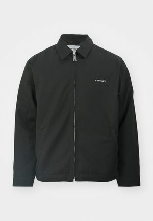 Zwarte jas van stevig materiaal, met een kraag en een rits aan de voorkant, en zijzakken. Logo weergegeven op de linker borst.