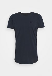 Námorně modré bavlněné tričko s kulatým výstřihem, krátkými rukávy a malým bílým logem na hrudi. Hladký povrch, standardní střih.