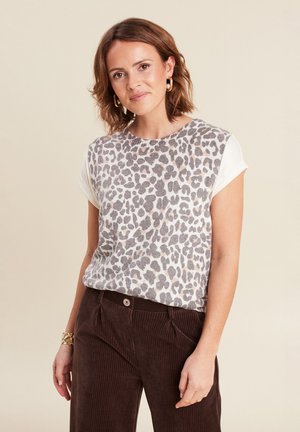 Leoprint-Oberteil mit samtiger Textur und kurzen Ärmeln, kombiniert mit dunkelbraunen Cordhosen im klassischen Schnitt und gerippter Textur.