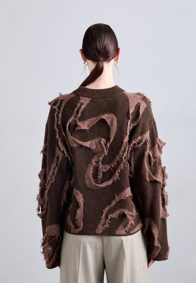 Brauner Strickpullover mit ausgefransten, strukturierten Details in einem wirbelnden Muster. Verfügt über einen Rundhalsausschnitt und einen oversized Schnitt.