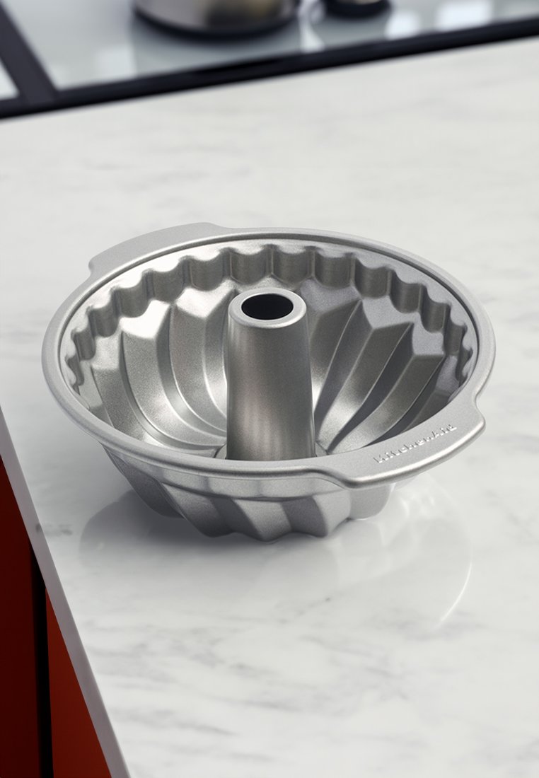 Teglia bundt in alluminio con tubo centrale, design rigato, colore argento e una maniglia su un lato per un facile sollevamento.