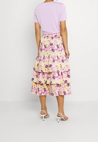 Kukallinen kerroshame, jossa on röyhelökerroksia vaaleanpunaisena, keltaisena ja violetina. Yhdistetty rentoon lila-paitaan ja valkoisiin remmikenkiin.