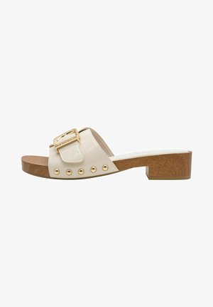 Beige slide sandals with a wide strap, gold buckle detail, metallic studs, and a wooden block heel. Smooth texture and rounded shape.