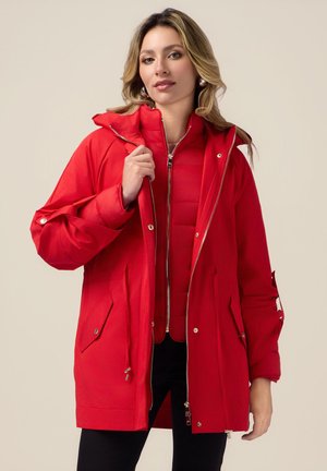 Rode parka met een rits aan de voorkant, capuchon en grote zakken. Voorzien van een gewatteerde voering en verstelbare manchetten. Gladde stof met een glanzende afwerking.