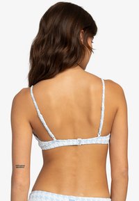 Svetloblúzový bikiny vrch s houndstooth vzorom, nastaviteľnými ramienkami a uzáverom na chrbte. Hladký povrch látky.