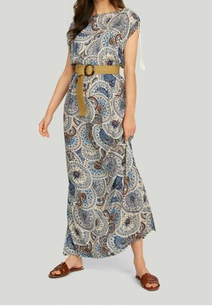 Frau trägt ein blau-braunes Paisley-Maxikleid mit breitem hellbraunem Gürtel und braunen flachen Sandalen, stehend vor einem schlichten hellen Hintergrund.