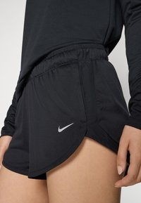 Mustat urheilushortsit, jotka on valmistettu kevyestä materiaalista. Niissä on joustava vyötärönauha ja pieni hopeinen Nike-logo sivussa.