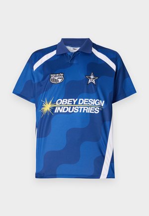 Sinine lühikeste varrukatega polosärk lainelise mustriga, valgete detailidega ja mitme logoga, sealhulgas "Obey Design Industries" ja täht.