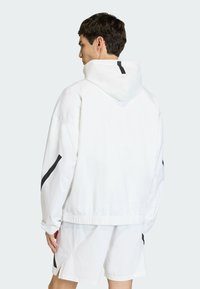 Biela kapucňa s uvoľneným strihom, s čiernymi akcentmi na rukávoch, elastickými manžetami a šnúrkou na kapucni.