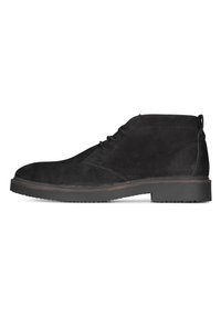 Botas de tobillo de ante negro con una textura suave, punta redondeada y diseño con cordones. Presentan una suela de goma duradera y suturas sutiles.