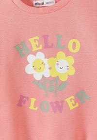 Chemise rose pour enfants avec des fleurs blanches et jaunes souriantes, et des lettres multicolores formant le mot « HELLO FLOWER » autour.