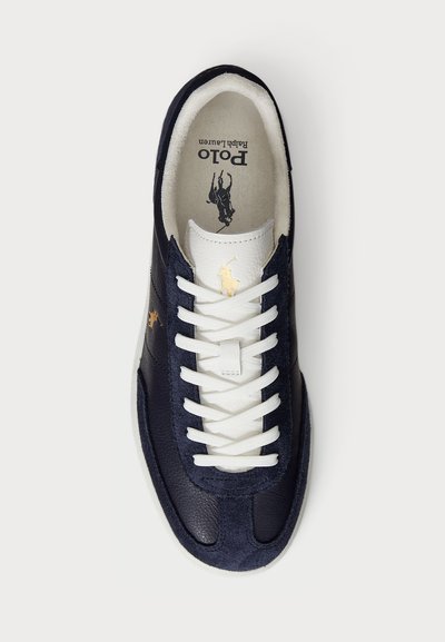 Marineblauwe leren en suede sneaker met witte veters. Beschikt over een gouden polo logo aan de zijkant en een zachte stoffen voering. Klassiek ontwerp en vorm.