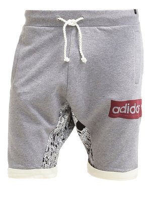 Shorts en coton gris avec bordure blanche, ornés d'un motif graphique et d'un patch logo rouge. Associés à un t-shirt en coton blanc ajusté et des baskets blanches.