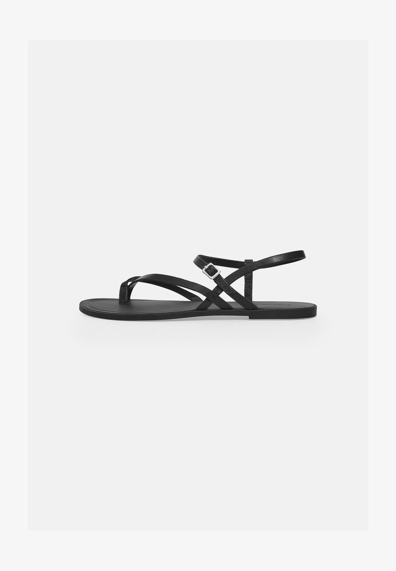 Svarte sandaler med flate såler som har flere tynne stropper og spennedetaljer. Glatt tekstur med et minimalistisk design.