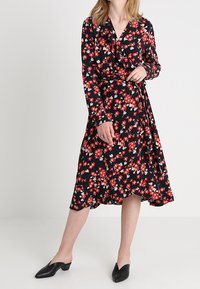 Musta kukkakuosi midi-mekko pitkillä hihoilla, röyhelökauluksella ja punaisella kukkakuviollla. Yhdistetty mustiin liukuhihnakkenkenkiin. Pehmeä kangas.