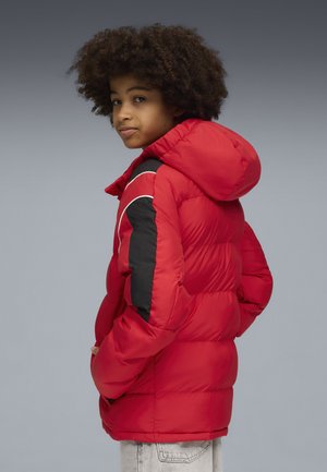 Chaqueta acolchada roja con capucha, que presenta ribetes negros en los hombros y las mangas, textura de canelones y bolsillos laterales.