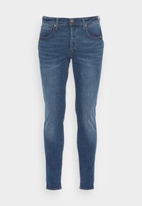 Jeans de mezclilla azul con corte ajustado, que cuentan con cinco bolsillos, una cremallera con cierre de botón y un ligero desgastado en toda la prenda.