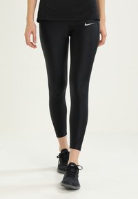Czarne legginsy sportowe wykonane z elastycznego materiału, charakteryzujące się dopasowanym krojem i małym, srebrnym logo Nike na biodrze.
