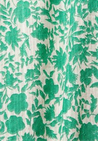 Motivo floreale verde su tessuto crema, caratterizzato da diverse forme di fiori e foglie con una superficie testurizzata. Il design include accenti sottili e dettagliati.