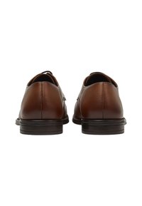 Chaussures en cuir marron avec une finition lisse, un bout rond et une semelle à faible relief. La vue arrière montre des coutures minimales et un design bas.